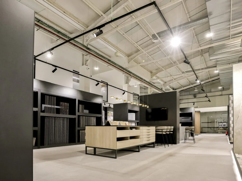 Vista general del showroom con estanterías negras de muestras y techo industrial