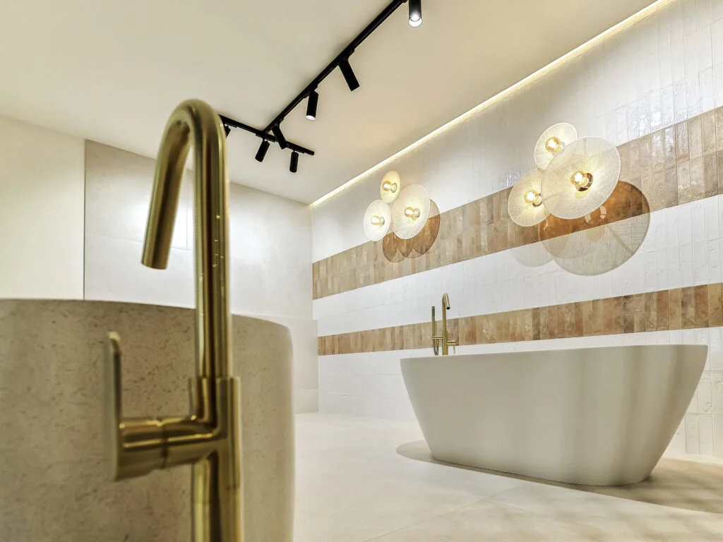 Grifo dorado de pie y bañera exenta en un ambiente del showroom