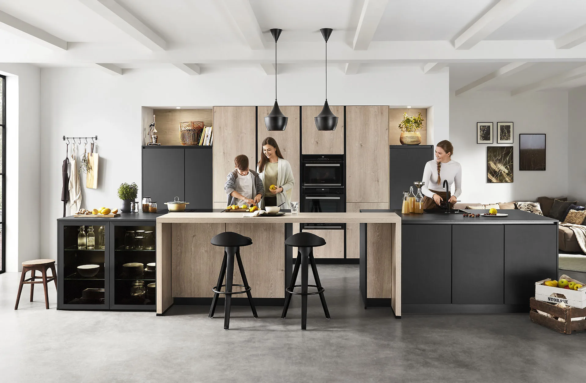 Cocina con isla negra y barra de roble con personas cocinando