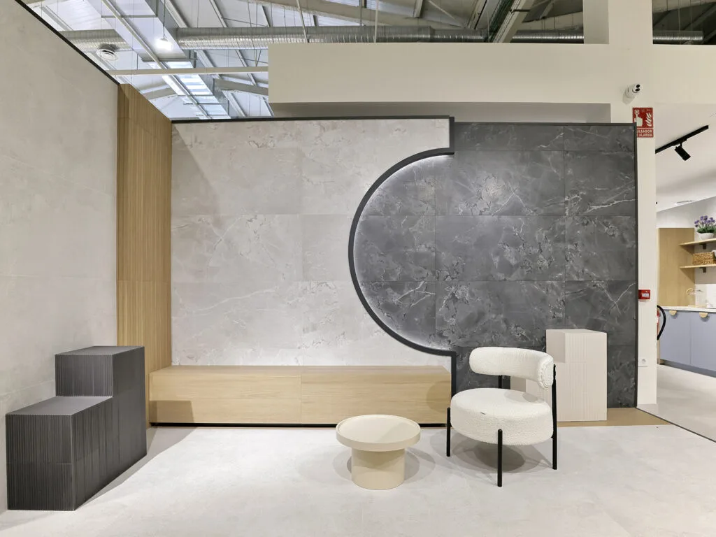 Ambiente con revestimiento gris en media luna y sillón blanco en el showroom