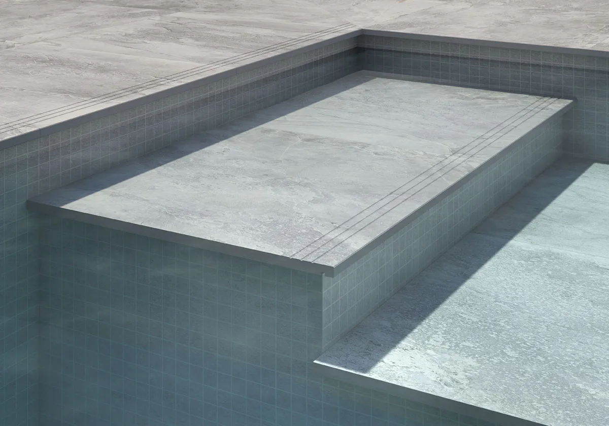 Detalle del borde de una piscina revestida en porcelánico gris mate