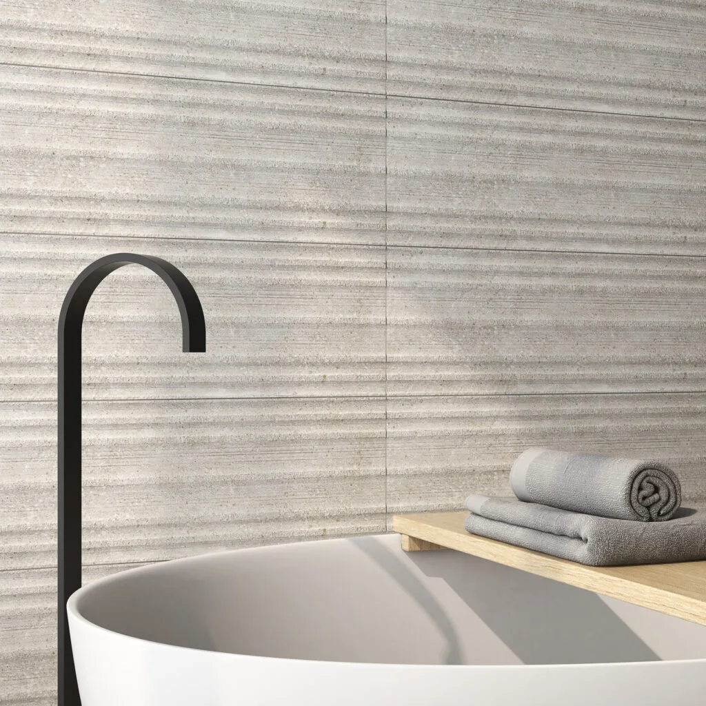 Revestimiento Underground gris con relieve lineal tras bañera blanca