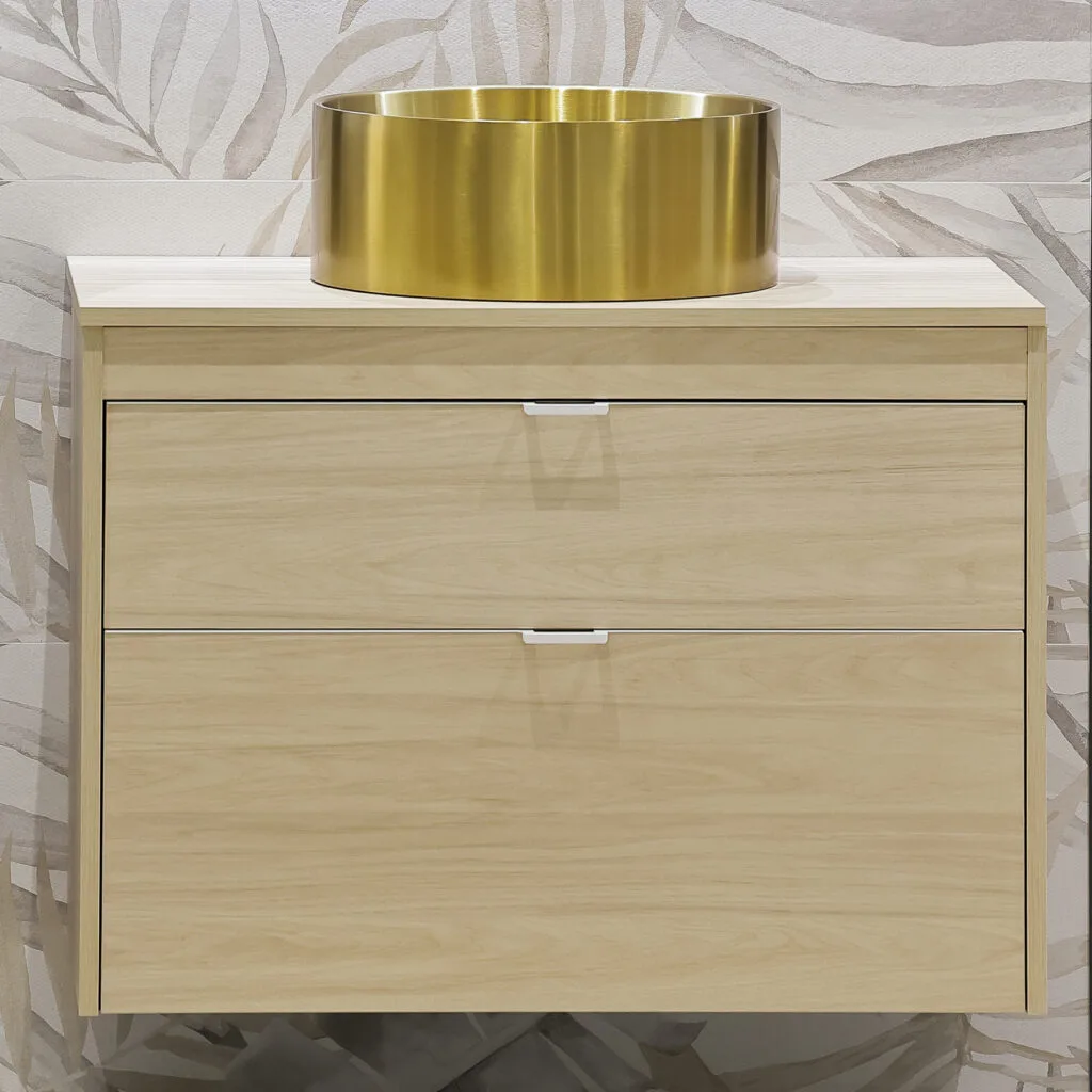 Lavabo de sobre encimera dorado sobre mueble de madera clara