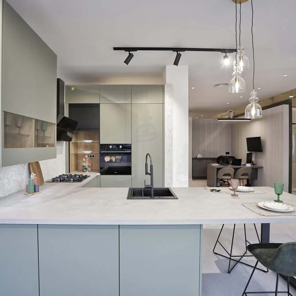 Cocina expuesta con isla gris claro, fregadero negro y lámparas de cristal
