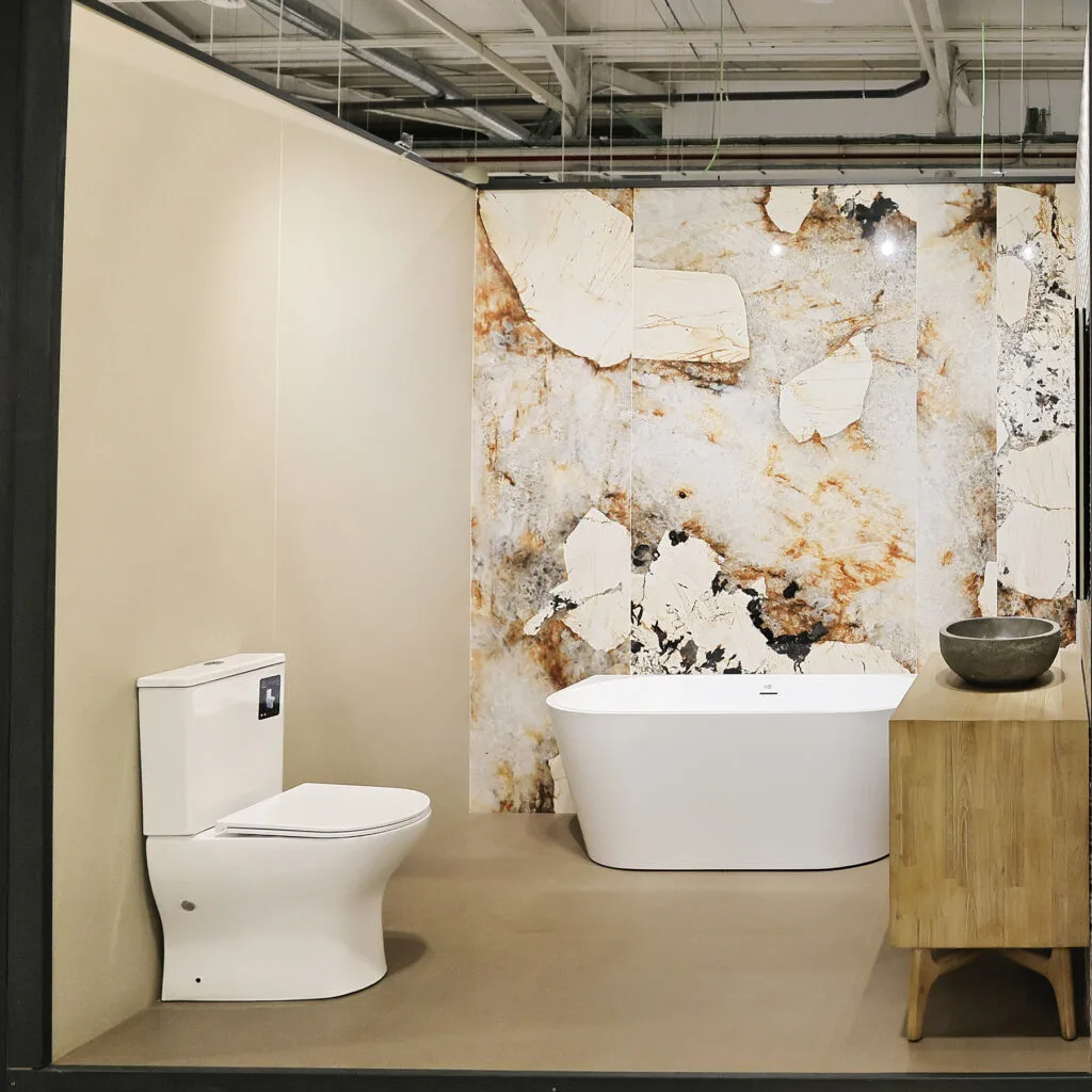 Ambiente de baño con bañera exenta y revestimiento efecto mármol multicolor en el showroom
