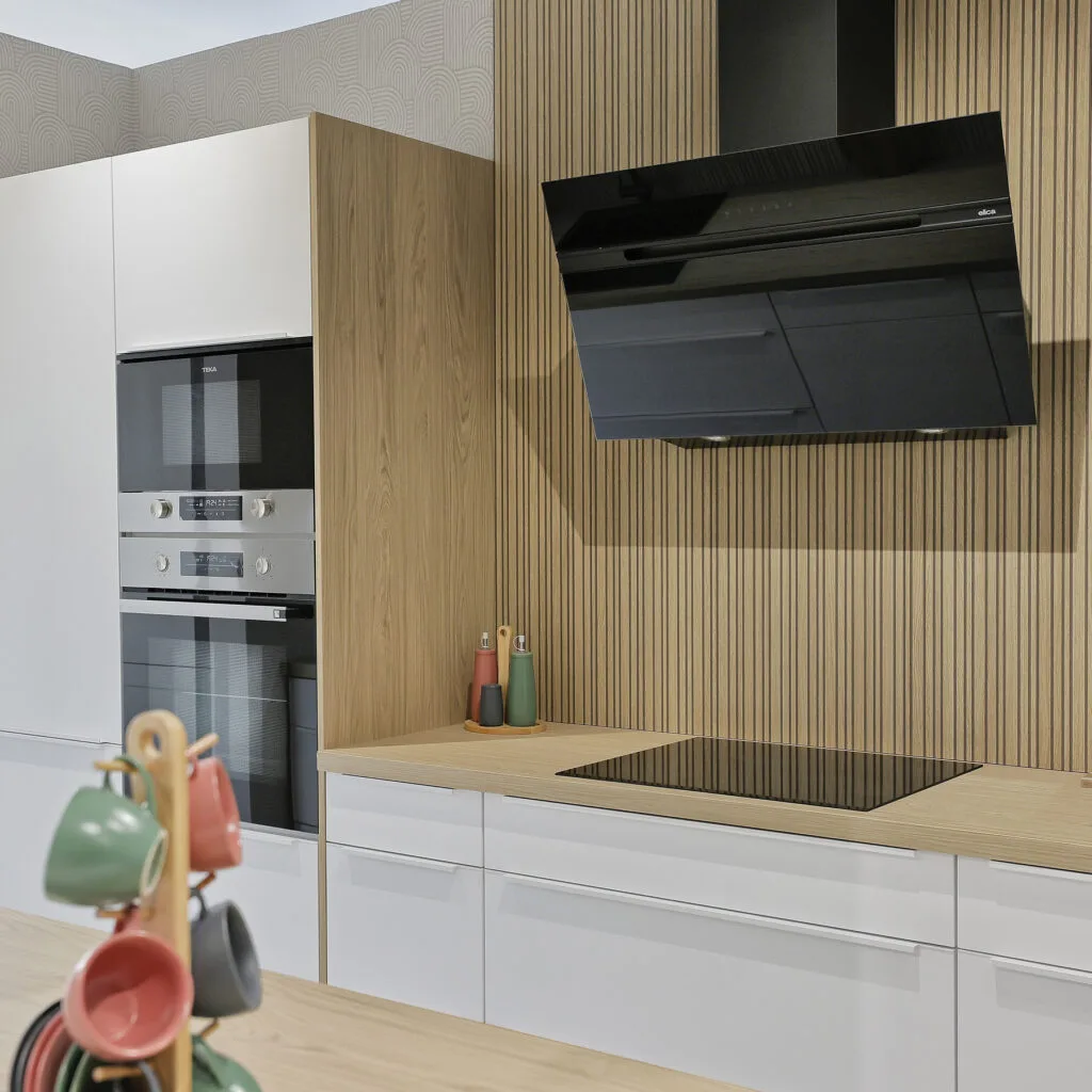 Cocina con columnas de hornos, panel de listones de madera y campana negra