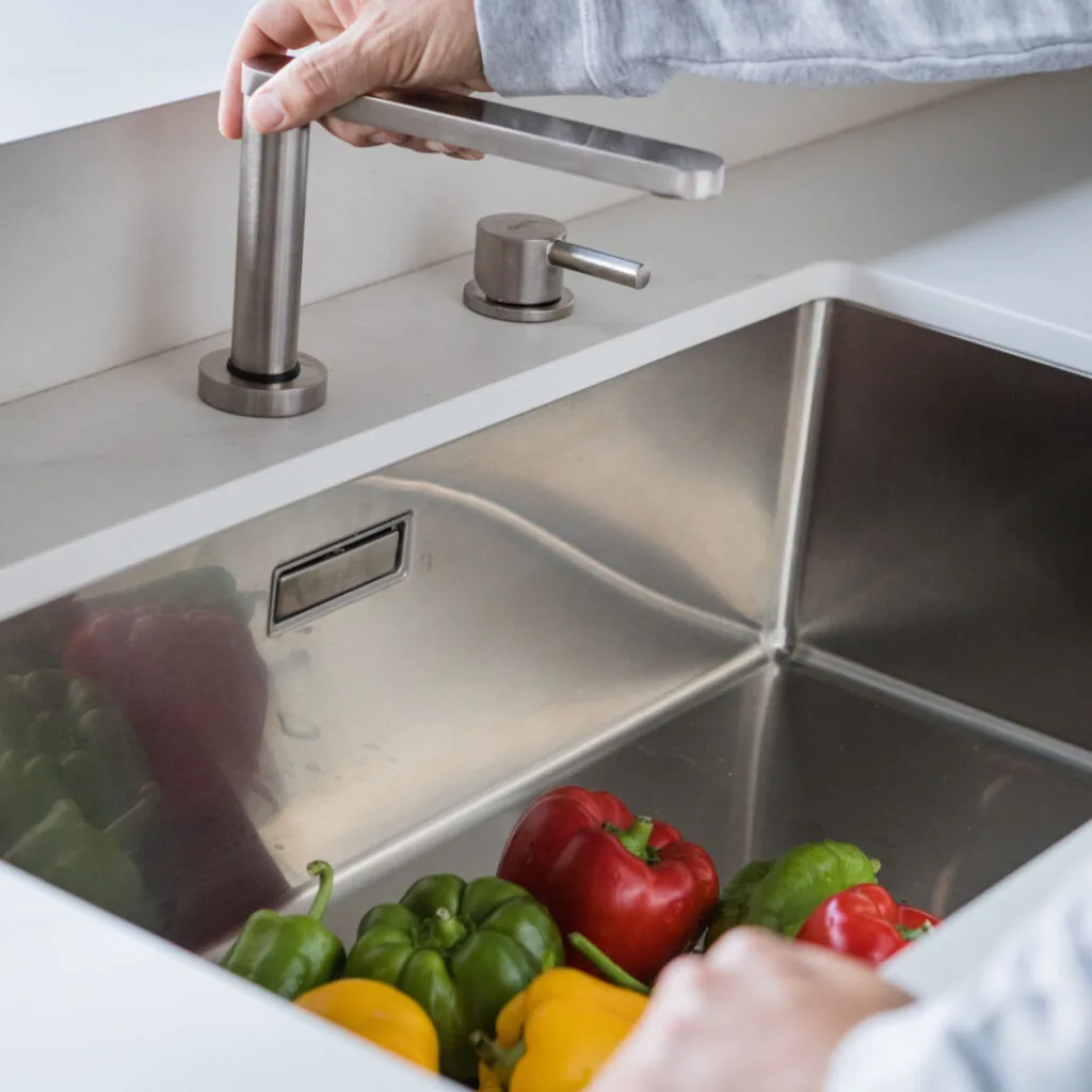Fregadero de acero con pimientos y grifo de acero cepillado