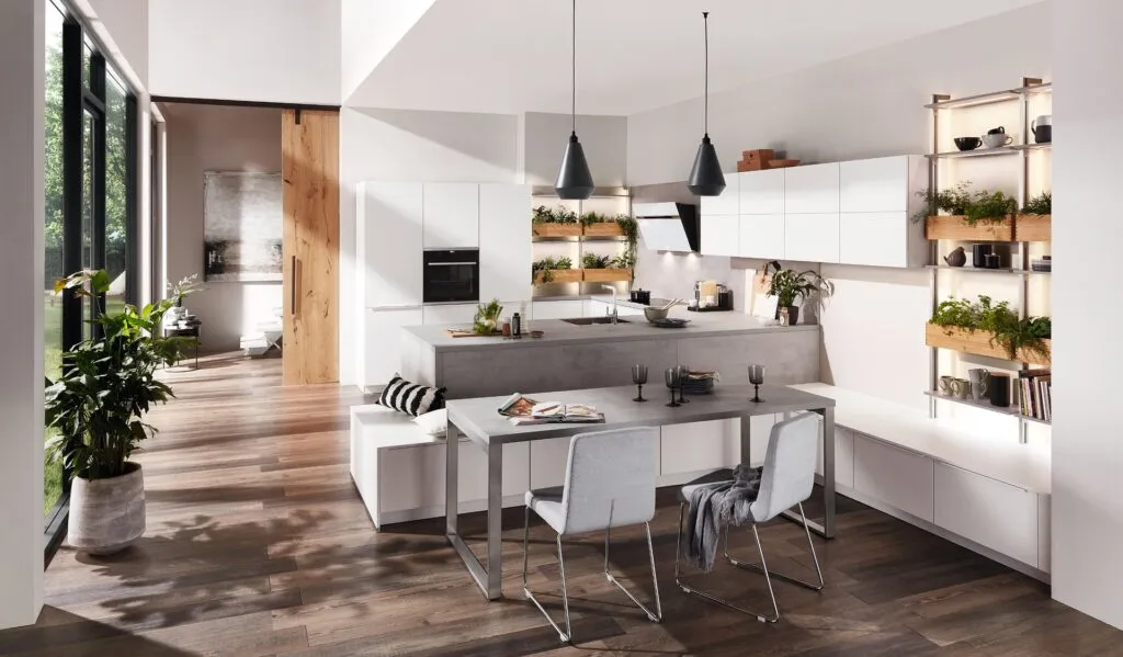 Cocina blanca con comedor integrado y estanterías de madera
