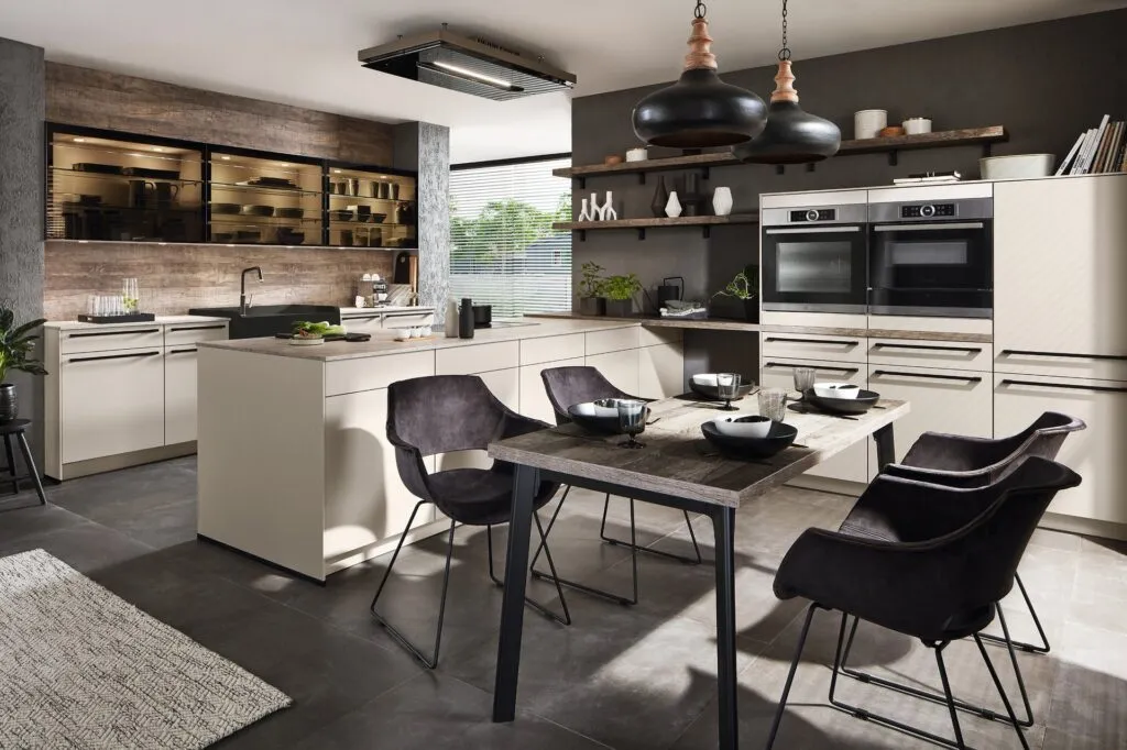 Cocina en tono crema con isla y comedor junto a pared de ladrillo