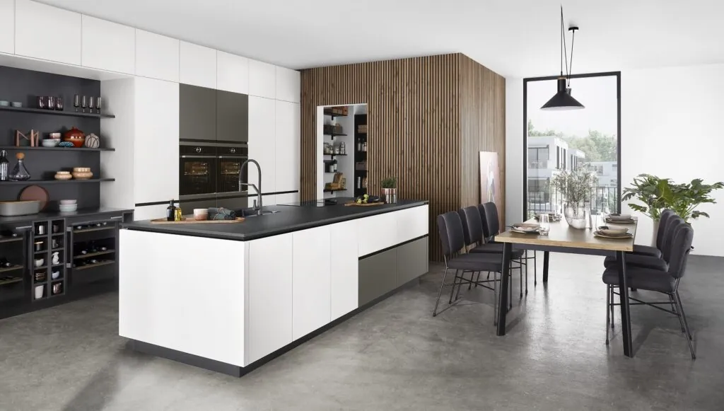 Cocina con isla blanca, pared de madera y comedor