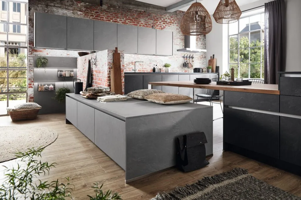 Cocina abierta con isla efecto hormigón y pared de ladrillo visto