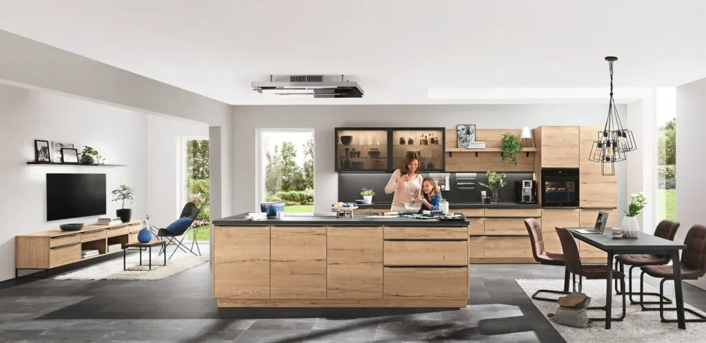 Cocina con isla de roble y columnas oscuras abierta al salón