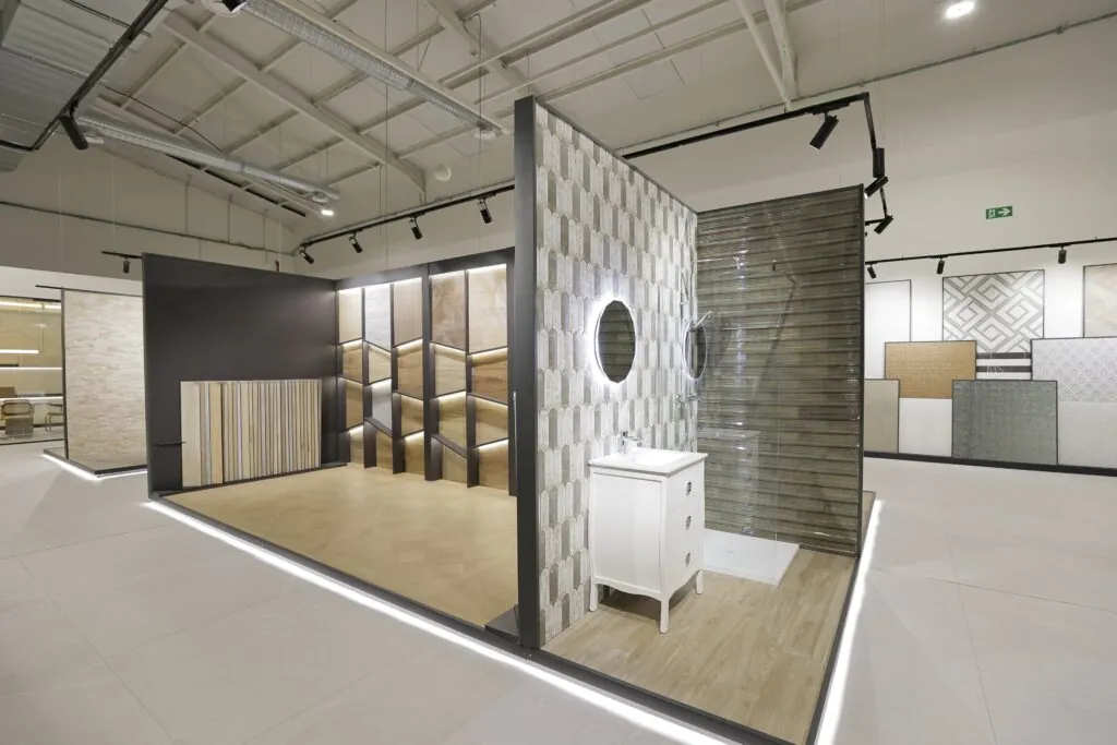 Baño expuesto con revestimiento gris, lavabo y espejo redondo