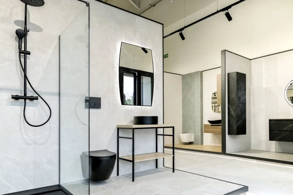 Ducha con grifería negra, inodoro negro y mueble de lavabo en el showroom