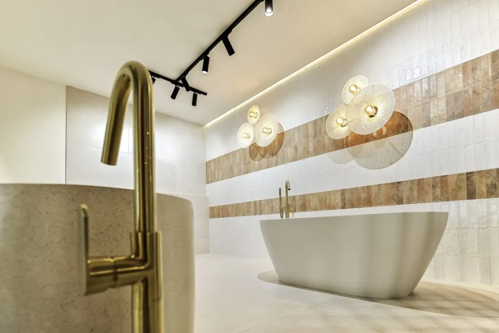 Grifo de pie dorado junto a una bañera exenta en el showroom